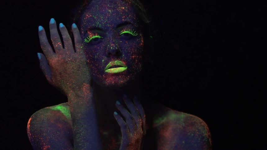 Person splashed with psychedelic colors under a blacklight