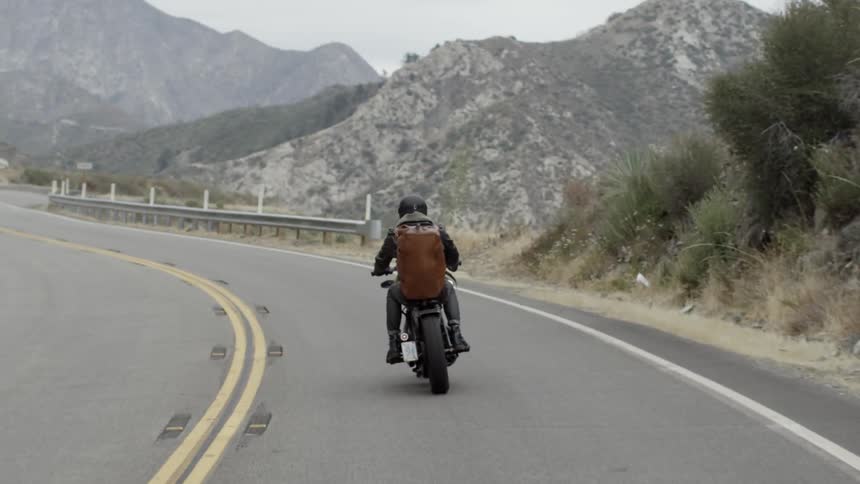 Person riding a motorcycle down a road on a cloudy day