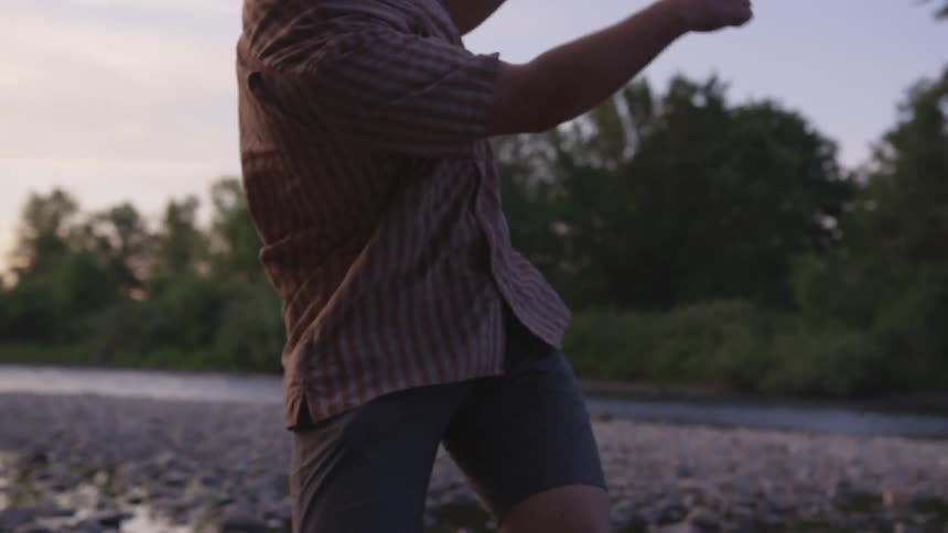 Child throws stone while standing near river
