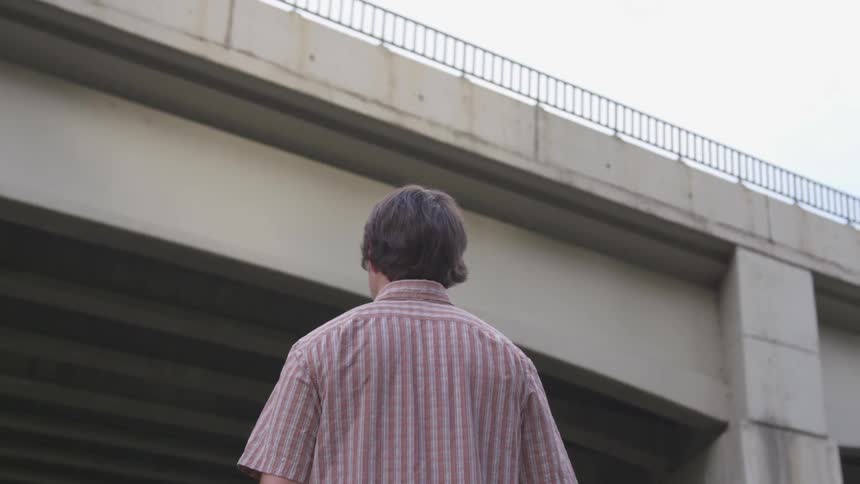 A man is walking towards a bridge above him