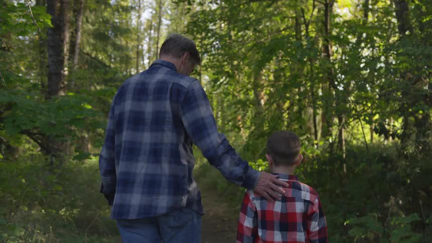 Father and son are walking through a forest