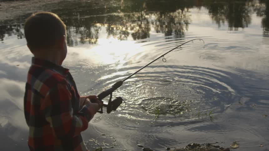 Boy along a river catching a fish