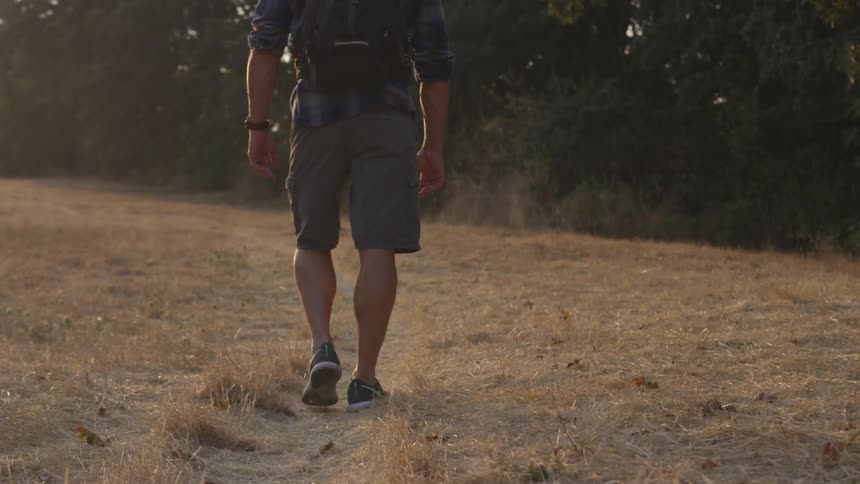 Man walks along walked path in dead grass