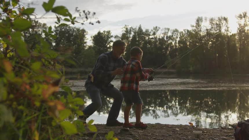 Father and son fly fishing on the river at sunset