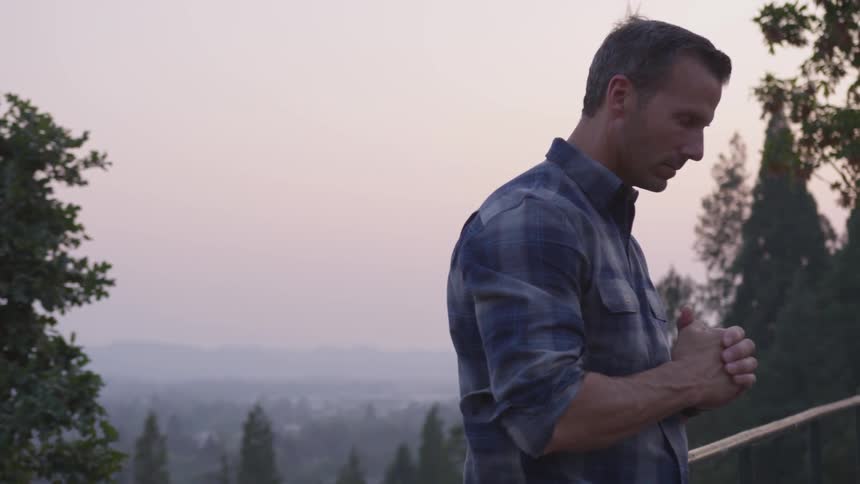 Man stands on mountain bridge meditating