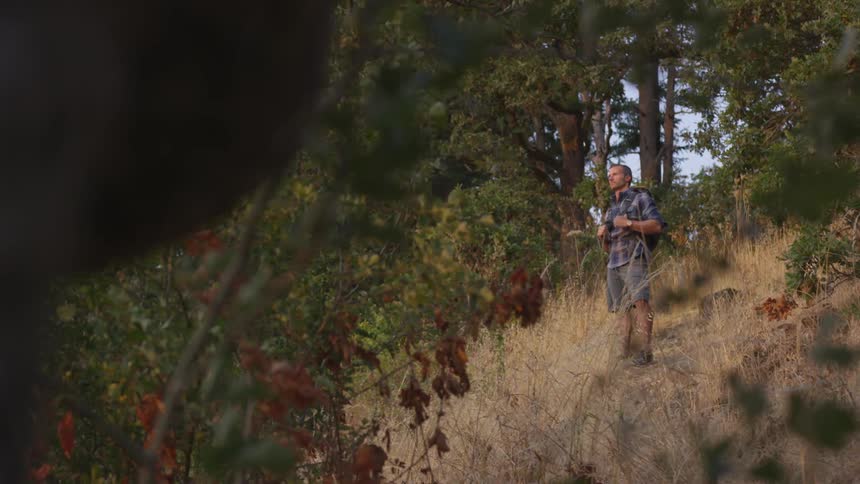 White man contemplating nature while in the middle of a hiking at the forest