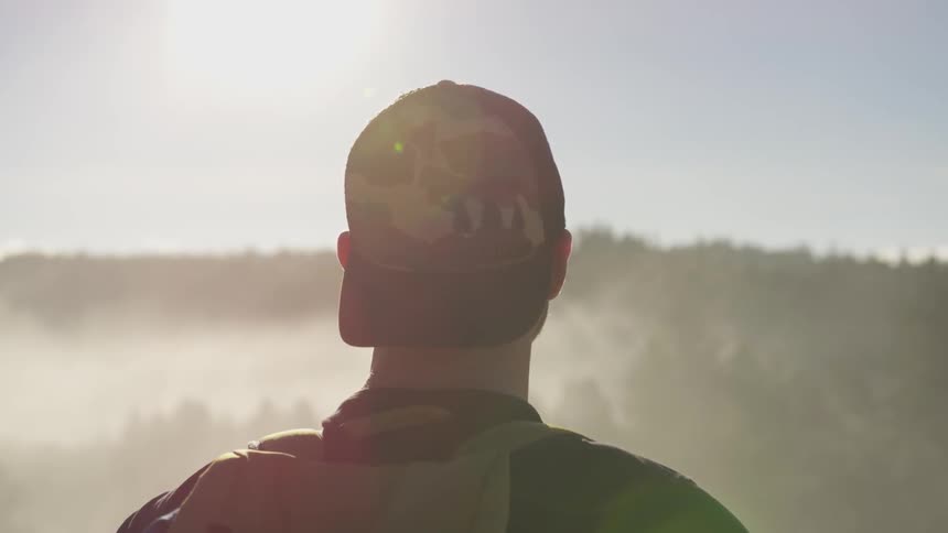 A man contemplates the horizon on the top of a hill at sunset