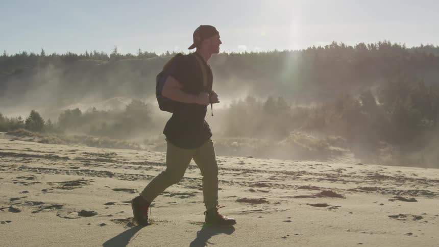 Man with backpack walks along desert hilltop