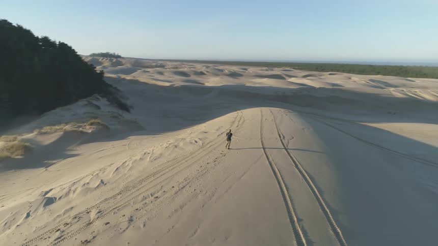 A man walks on sand dunes