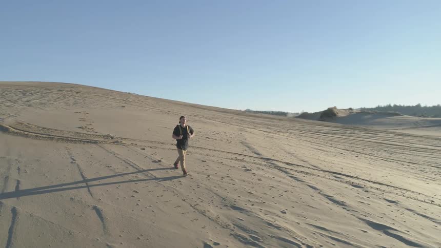 A man is walking through a desert alone in the afternoon