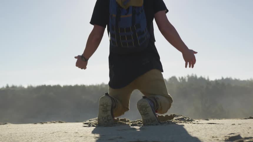 A man standing at the edge of a cliff and falling to his knees