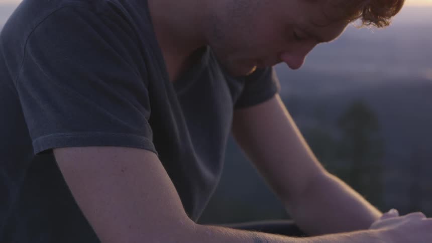Man sits down and thinks at sunset