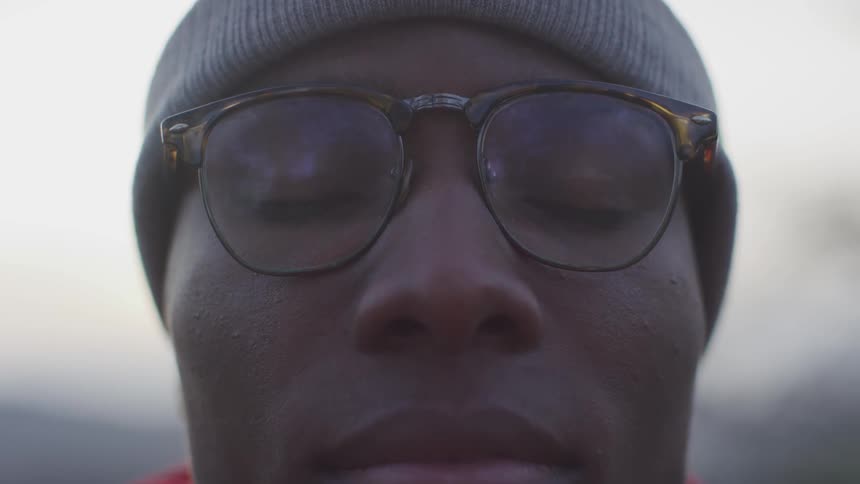 Close up of black man with glasses blinking
