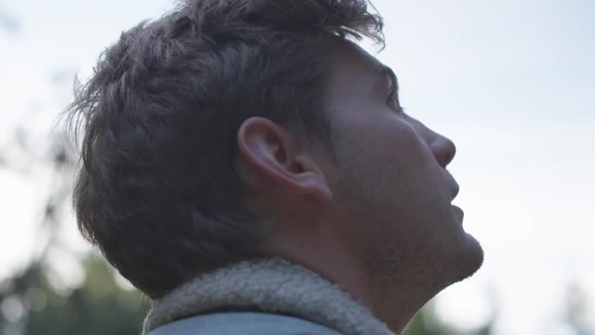 Man stands outside in winter looking up at the sky