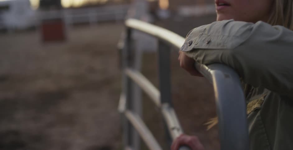 Woman looking into a corral while leaning on some railing