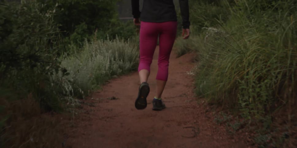 Woman walking down a small dirt path in the wilderness