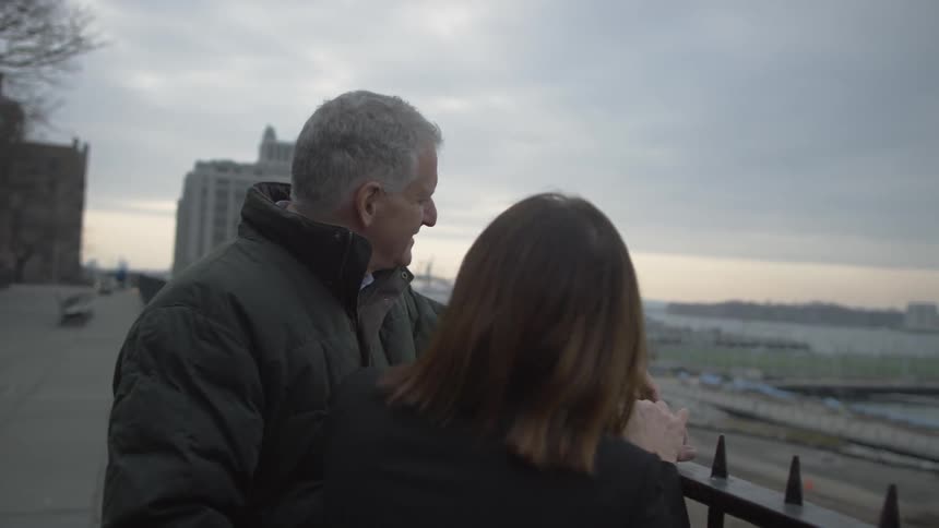 Elderly couple talking while leaning on an elevated railing