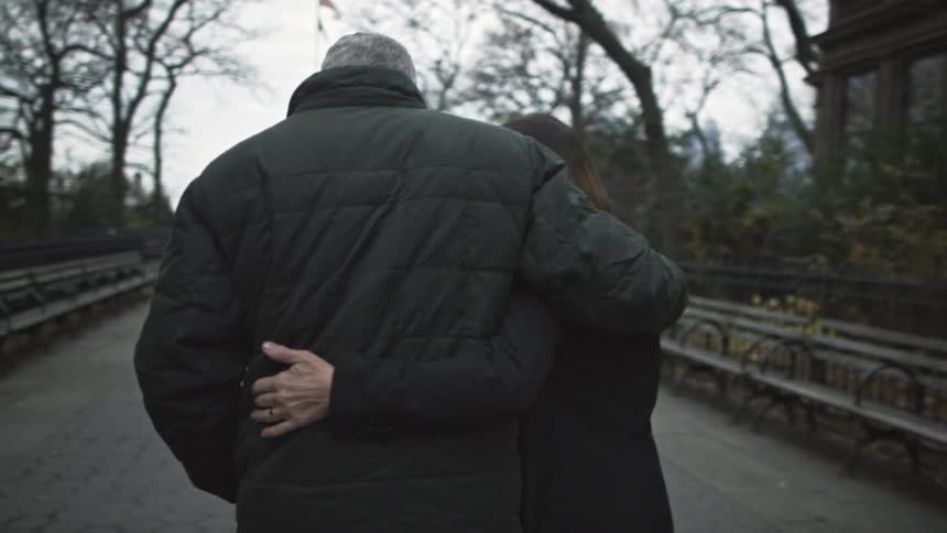 A man and woman embracing as they walk in a city area