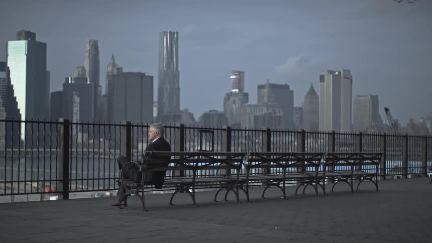 Man sits on a bench overlooking the city and river
