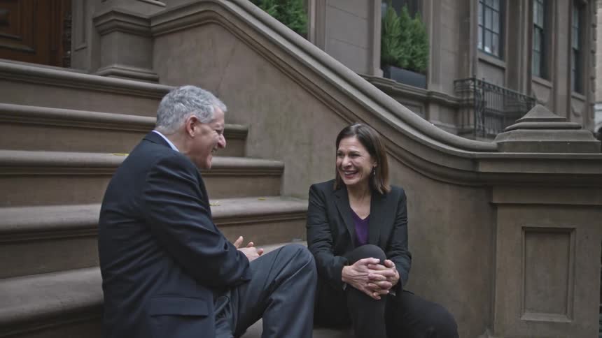 A man and woman sitting and chatting on a city stoop