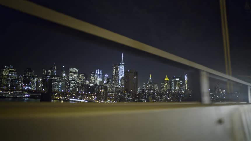 A vehicle crossing a city bridge at night