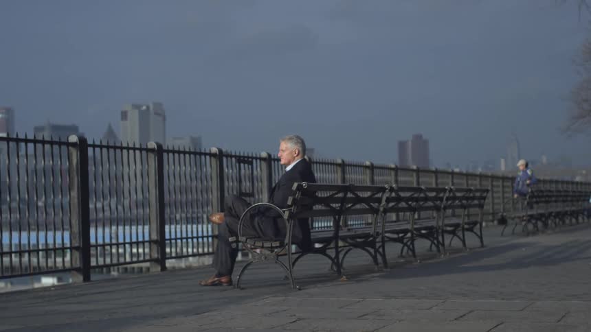 A man sits on a bench on a cloudy day