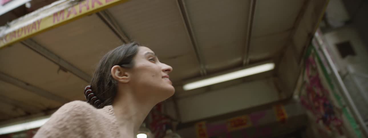 Woman with brown hair looks up while walking in city