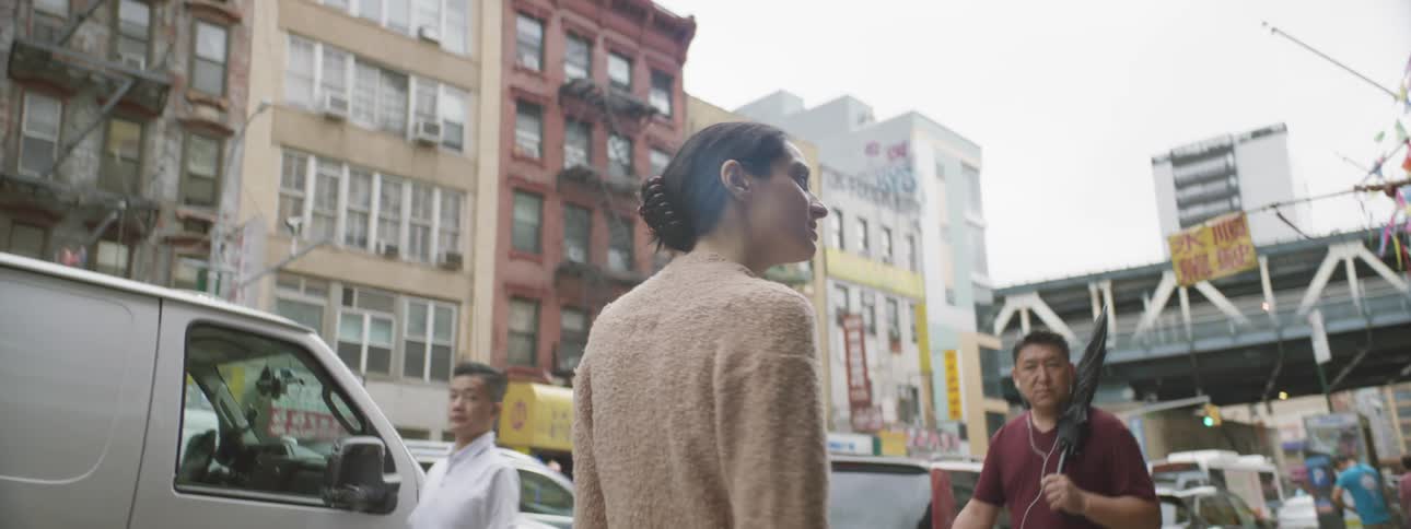 Woman walking walking down street around tall buildings