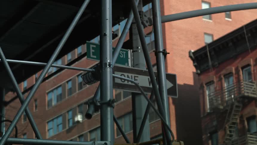 City street signs and scaffolding under a bridge