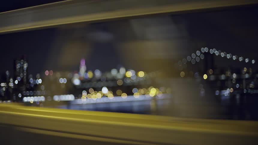 A vehicle crossing a city bridge at night