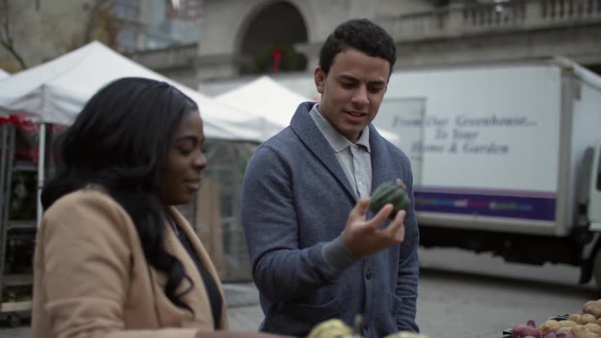 Couple discussing fruit while at an outdoors fruit stand