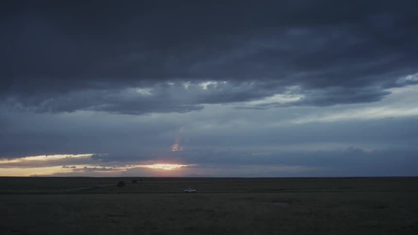 A truck drives down a country road through large fields at dusk