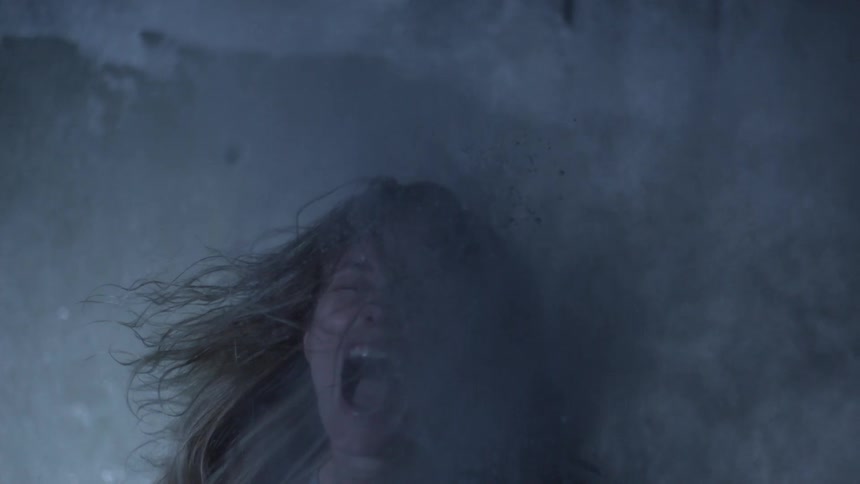 A woman with long, blonde hair turning and screaming as a cloud of dust hits her