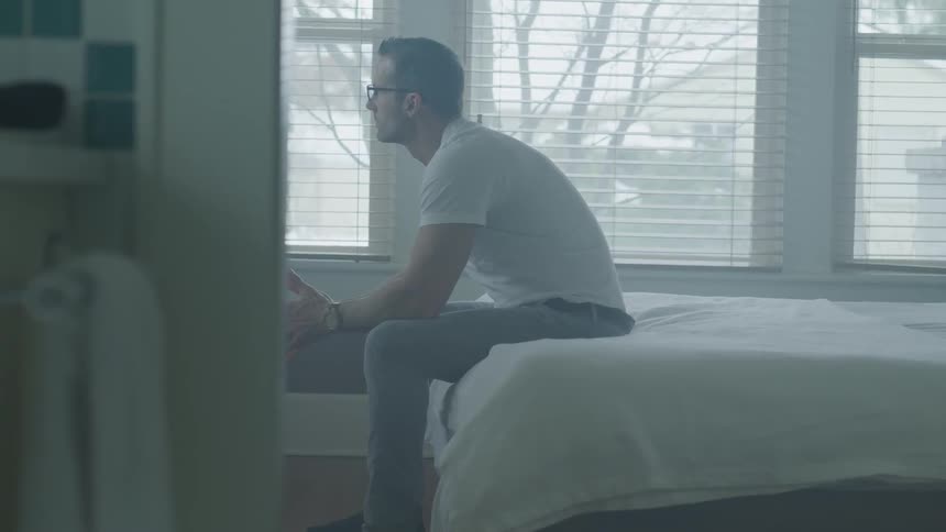 Man Sitting And Thinking On Bed