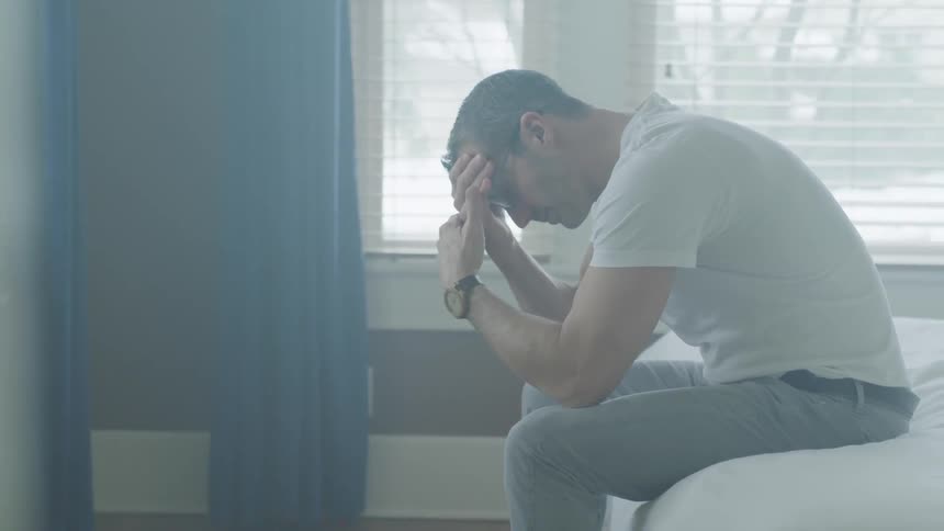 Man Sitting And Thinking On Bed