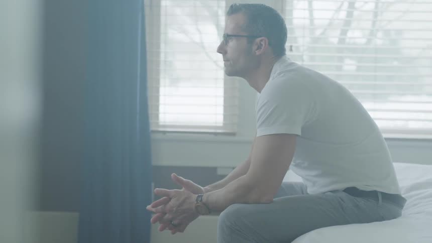 Man Sitting And Thinking On Bed