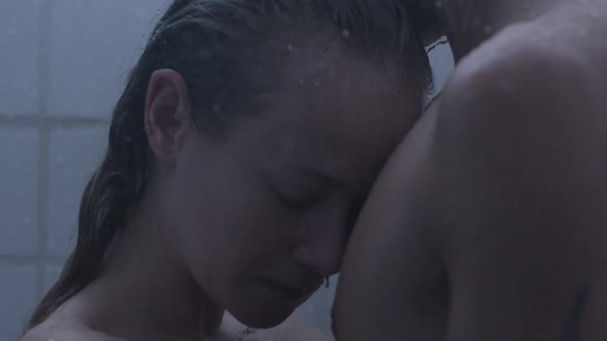 A woman rests her head on a mans chest as they are standing in the shower