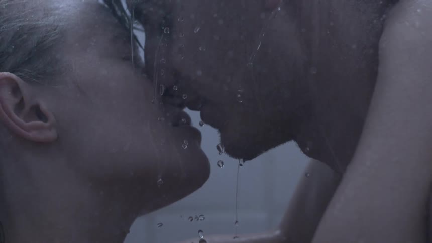 Man and woman kiss as water pours on them
