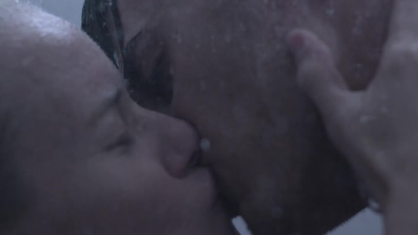 Man and woman kiss as water pours on them