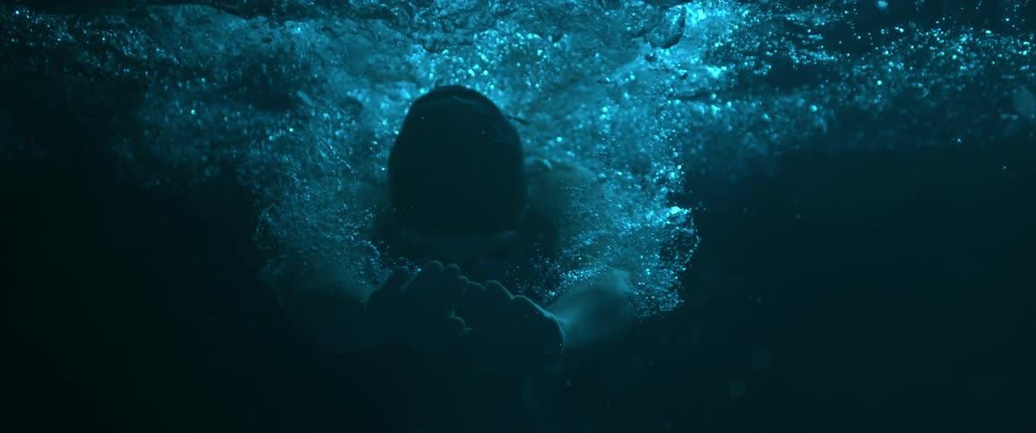 A person dives underwater and begins to swim
