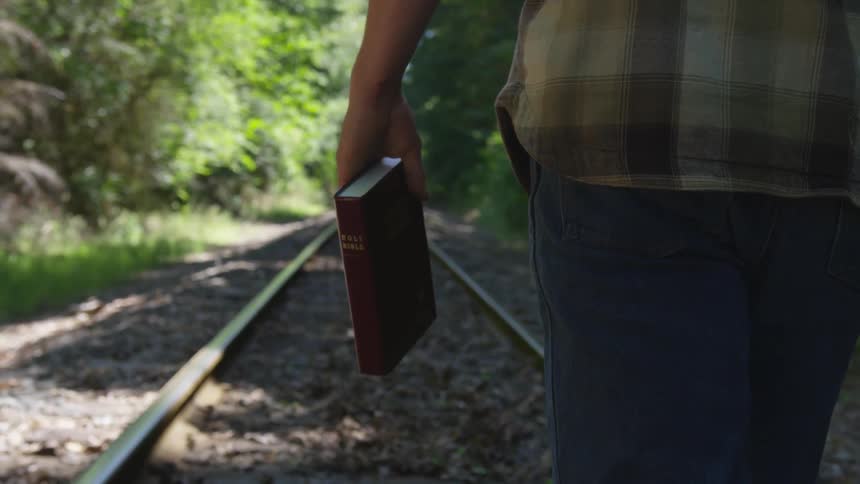 Man With Bible Walking On Train Tracks