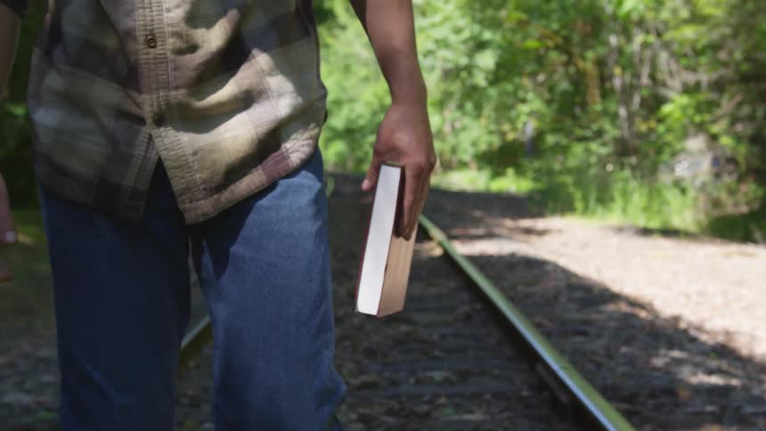 Man With Bible Walking On Train Tracks