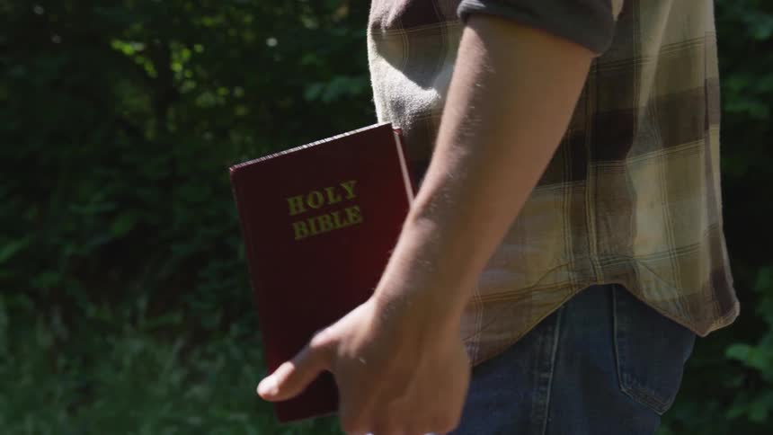Man With Bible Walking On Train Tracks
