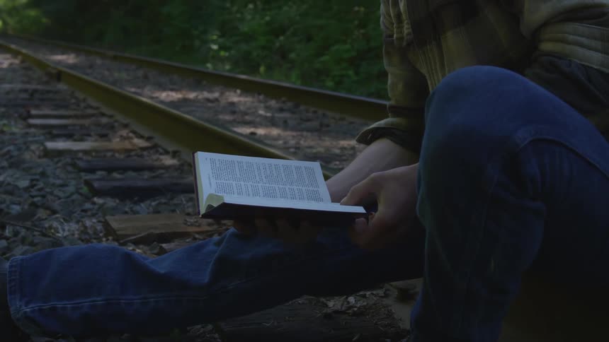 Man With Bible Walking On Train Tracks