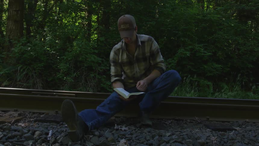 Man With Bible Walking On Train Tracks