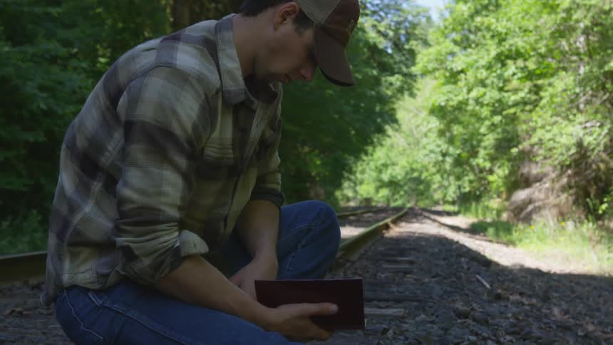 Man With Bible Walking On Train Tracks