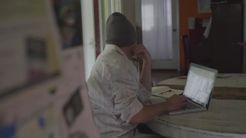Man Working On Computer At Kitchen Table