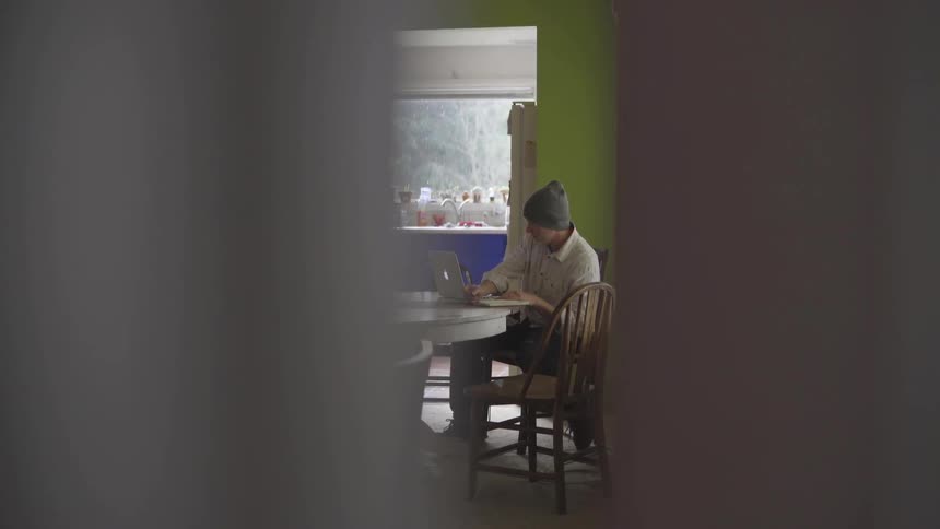 Man Working On Computer At Kitchen Table