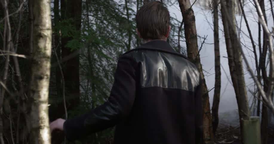 A young man hikes through a dense forest
