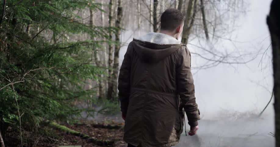 Man walking in the woods with fog on the ground